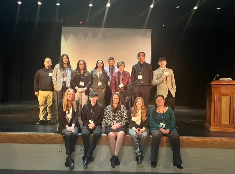 students in front of screen on stage